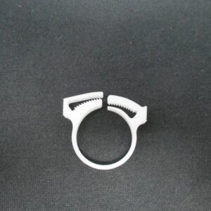 White plastic serrated tubing clamp on black cloth